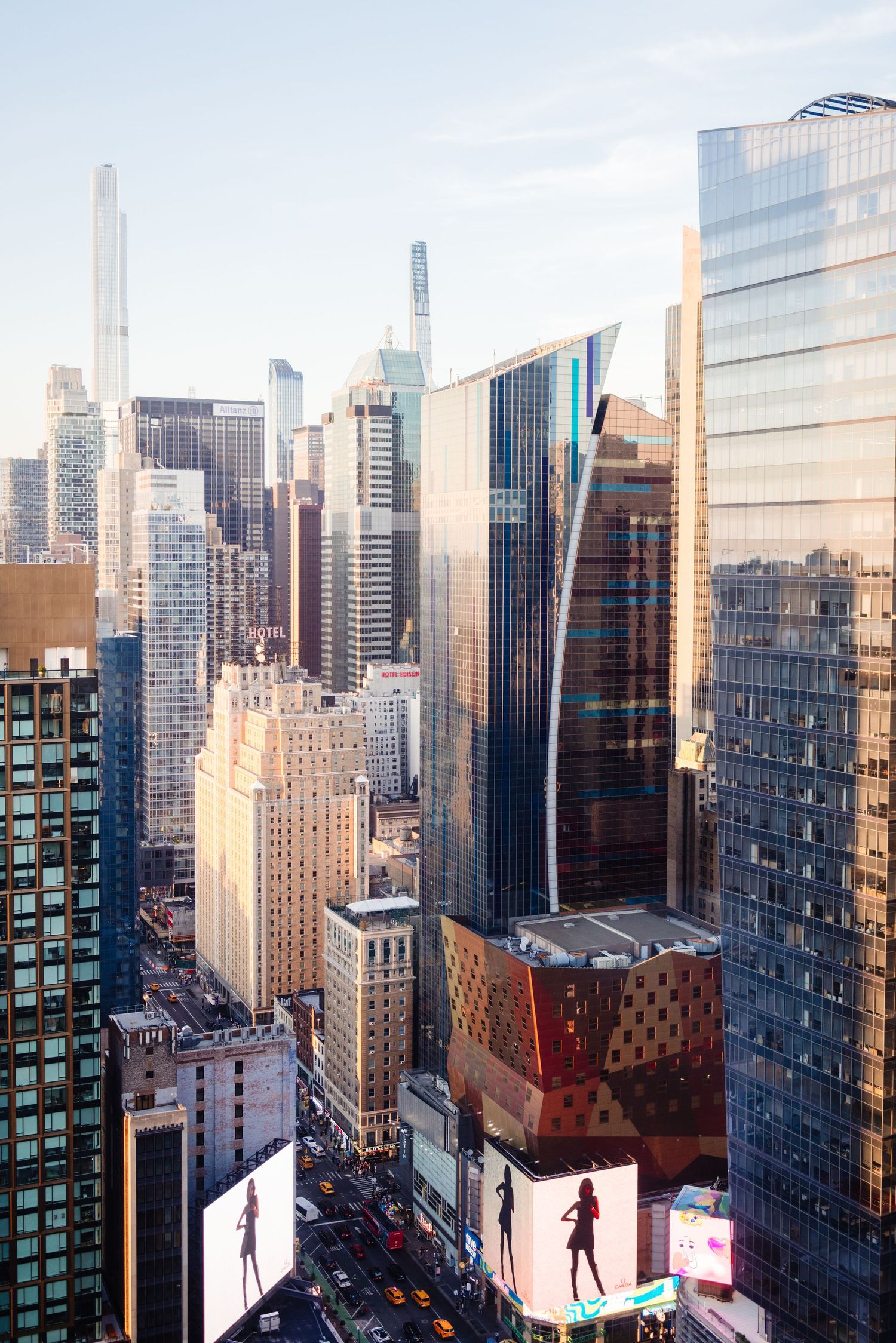 Manhattan skyline view featuring modern skyscrapers and billboards in bright daylight.