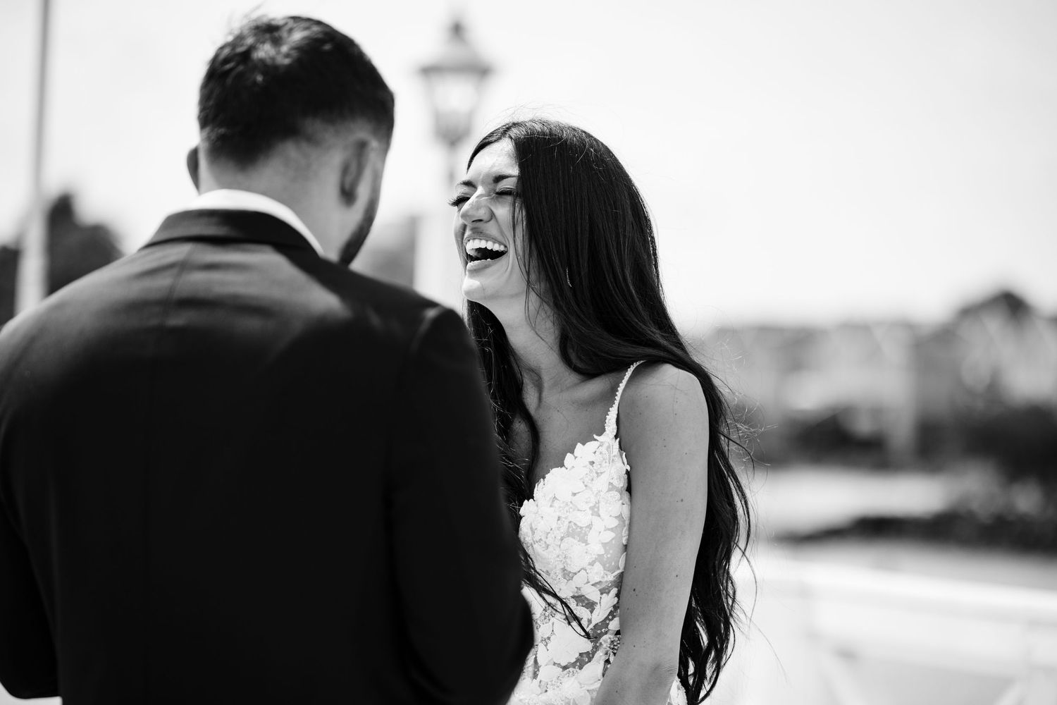 Black and white candid moment of joy during waterfront wedding ceremony.