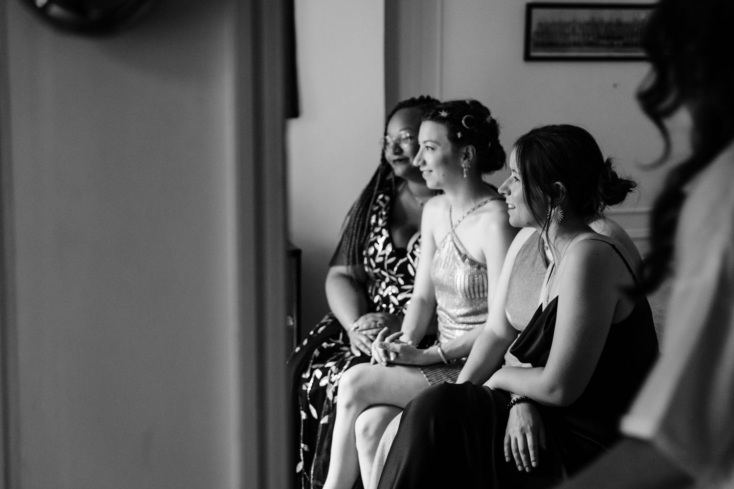 Three women sitting together share an intimate moment in black and white photography.