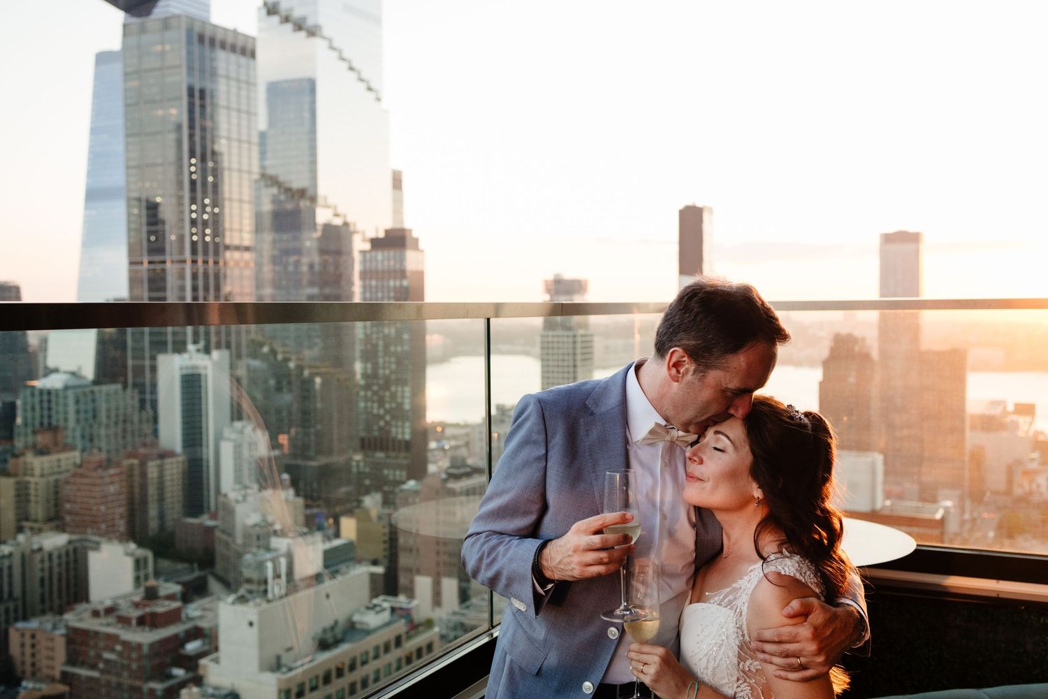 Romantic rooftop moment against New York City sunset skyline.