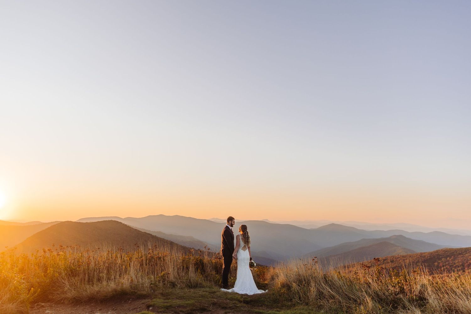 Panoramic mountain vista at sunset with couple silhouetted against the fading light.