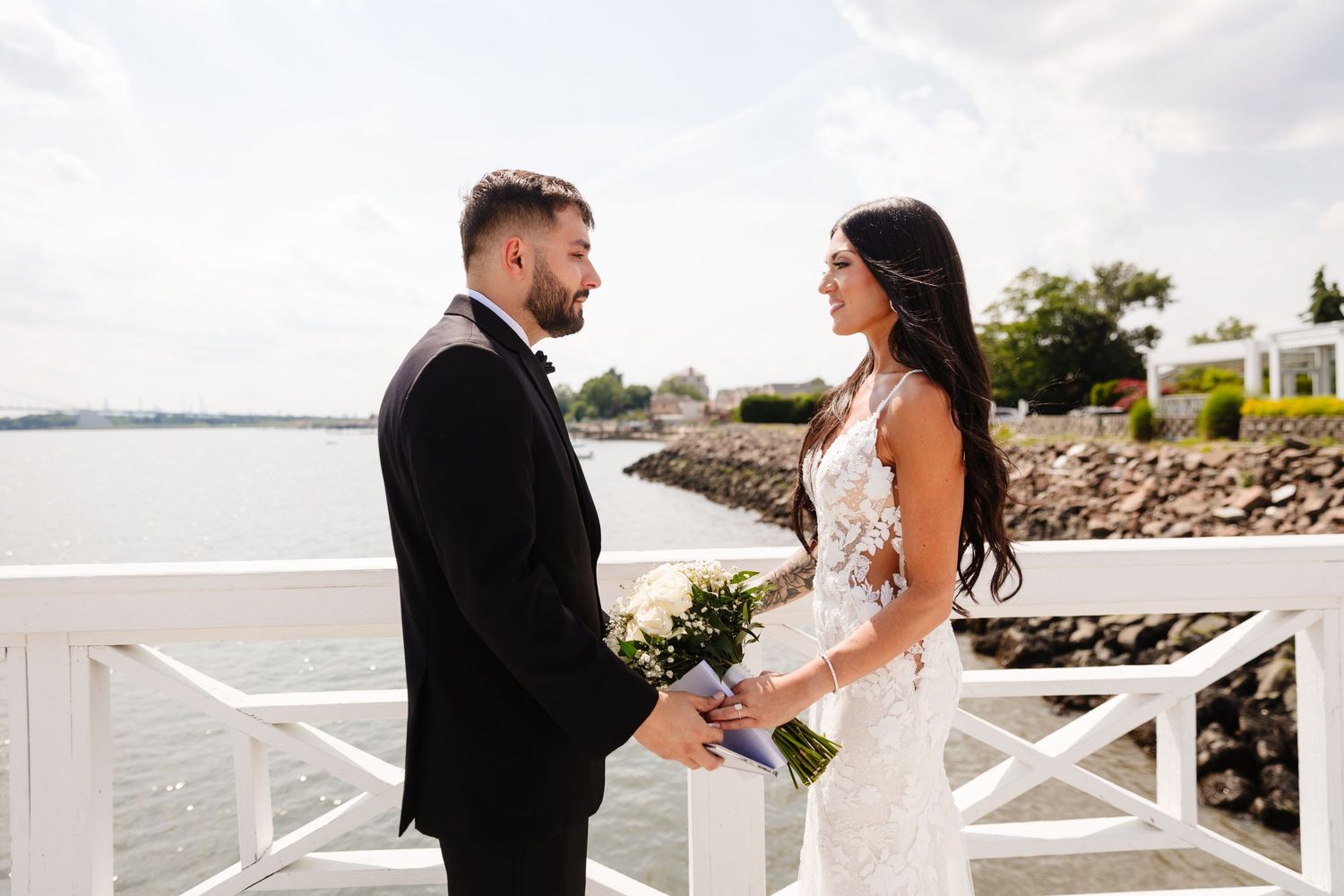 Couple shares romantic moment on waterfront deck with ocean view in background.
