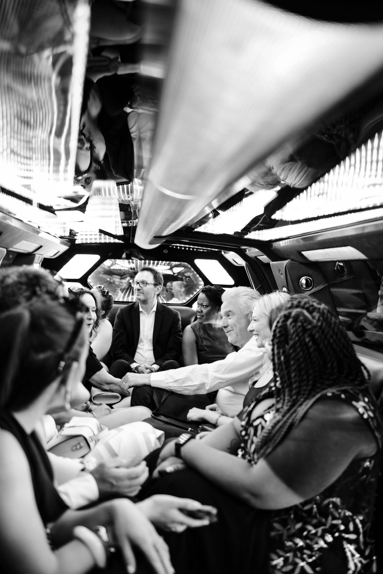 A black and white photo of guests socializing in a limo or party bus interior.