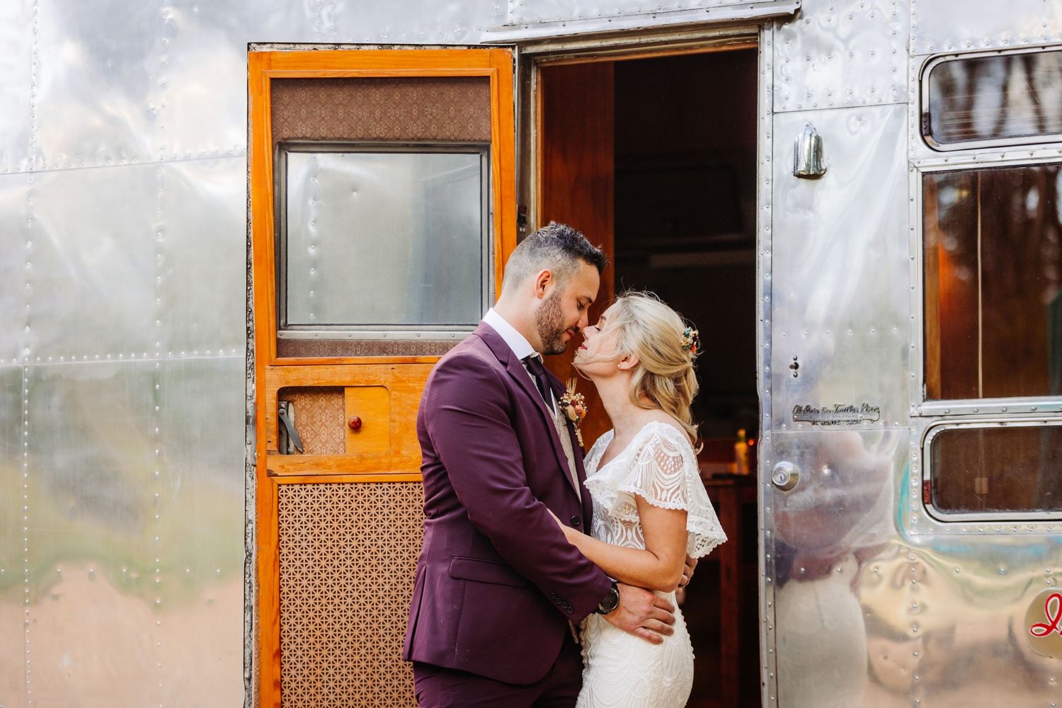 A romantic moment captured in the doorway of a vintage silver Airstream trailer.