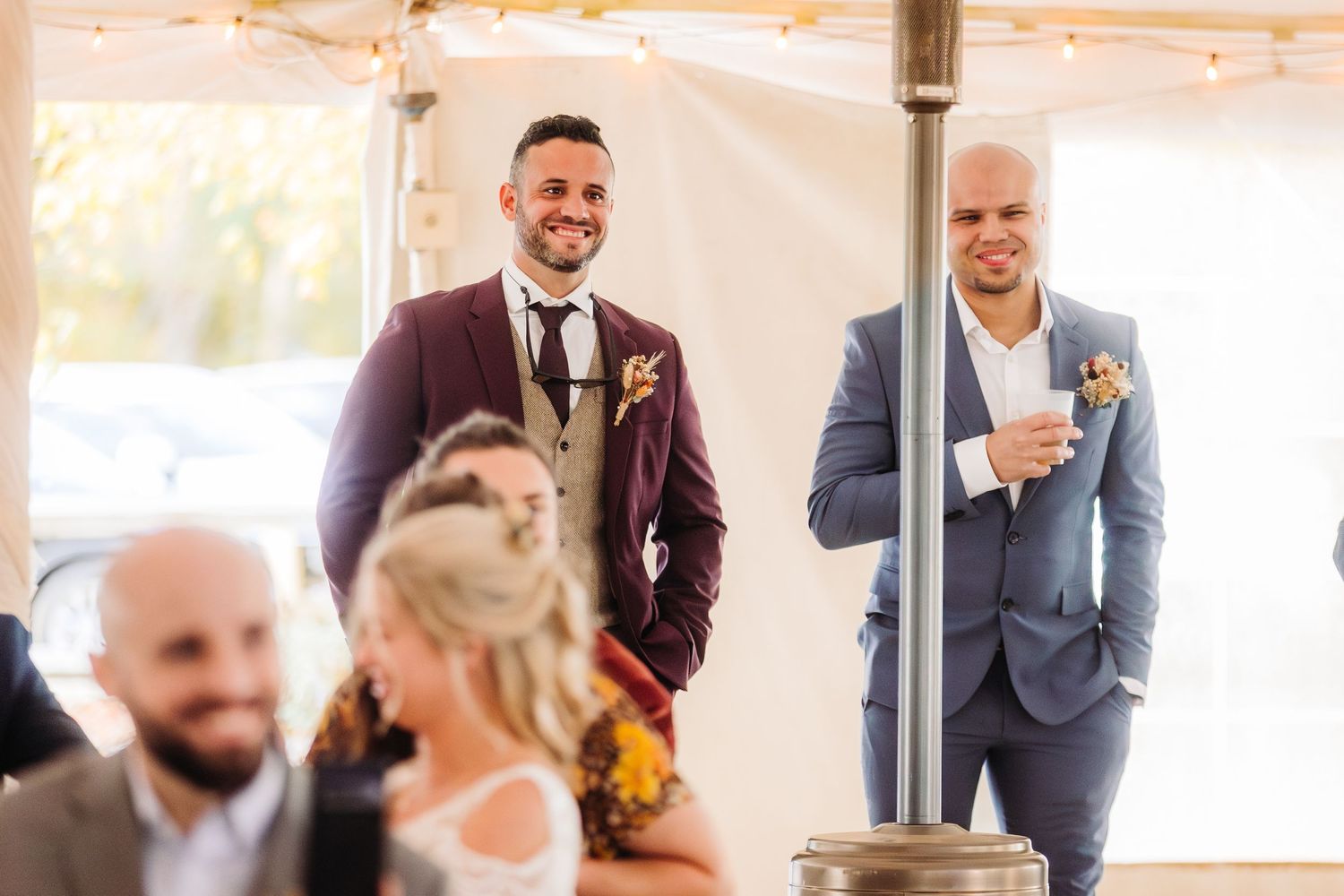 Wedding guests in formal attire socializing at an indoor reception.