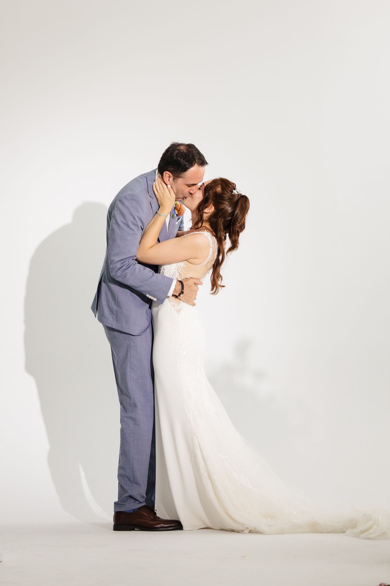 A tender moment between newlyweds against a white backdrop.
