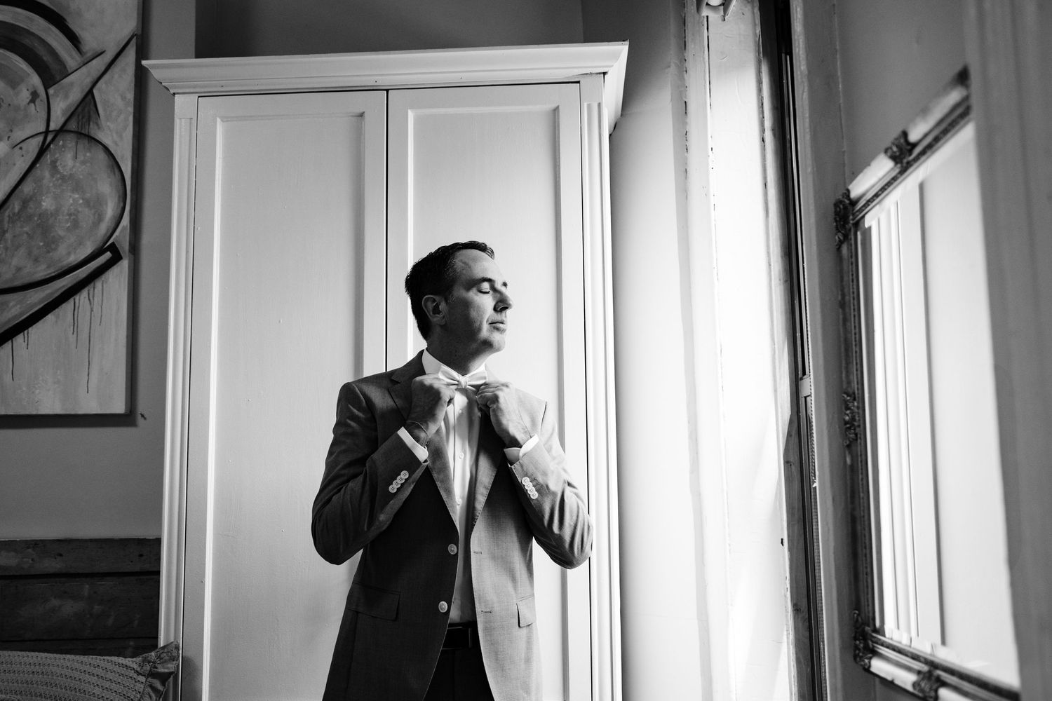Black and white series of someone adjusting their tie in front of a window.