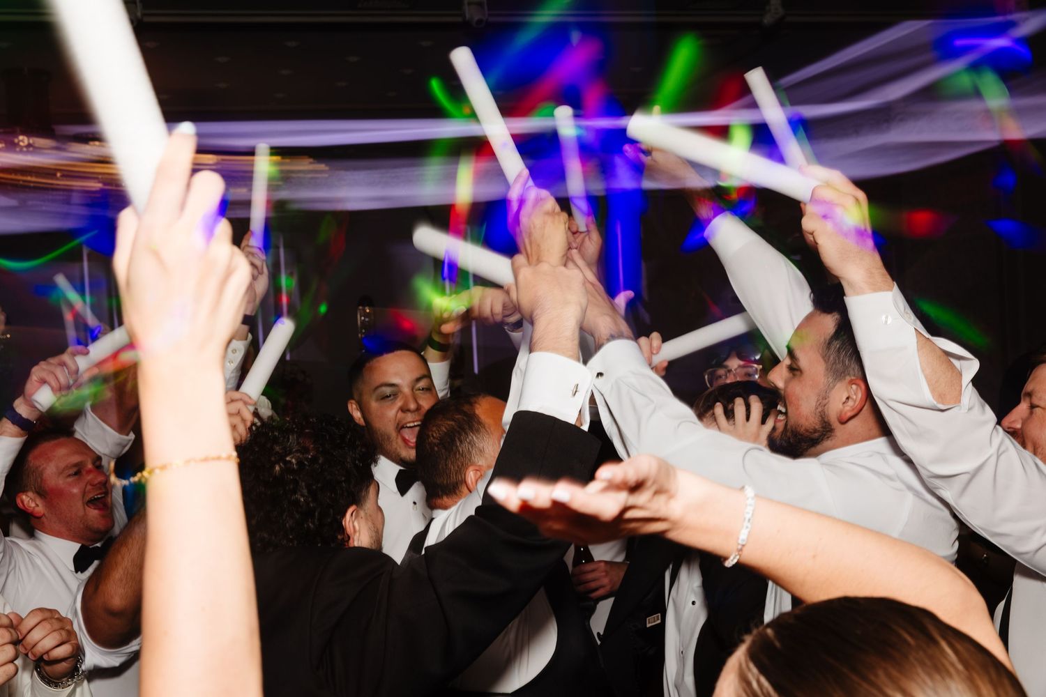 Nightclub atmosphere with party-goers dancing and celebrating under colorful lights.