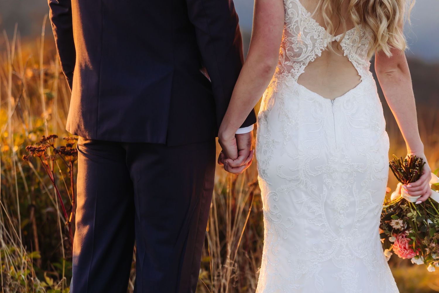 Close-up details of lace wedding dress and formal attire against mountain backdrop at sunset.