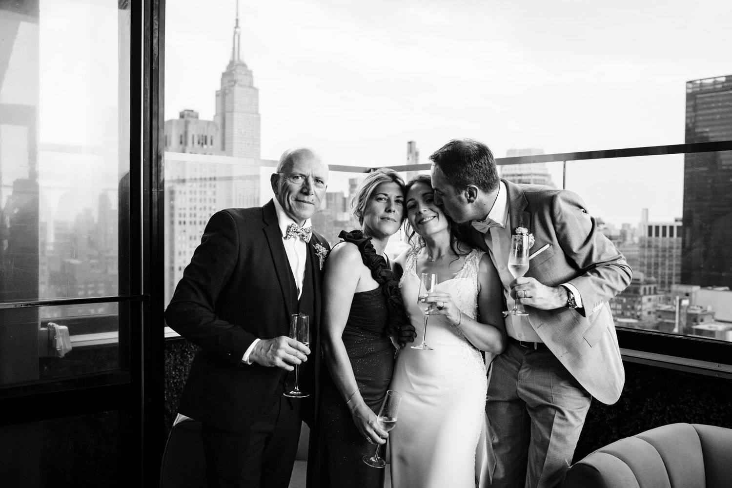 Wedding celebration on a rooftop terrace overlooking New York City skyline in black and white.
