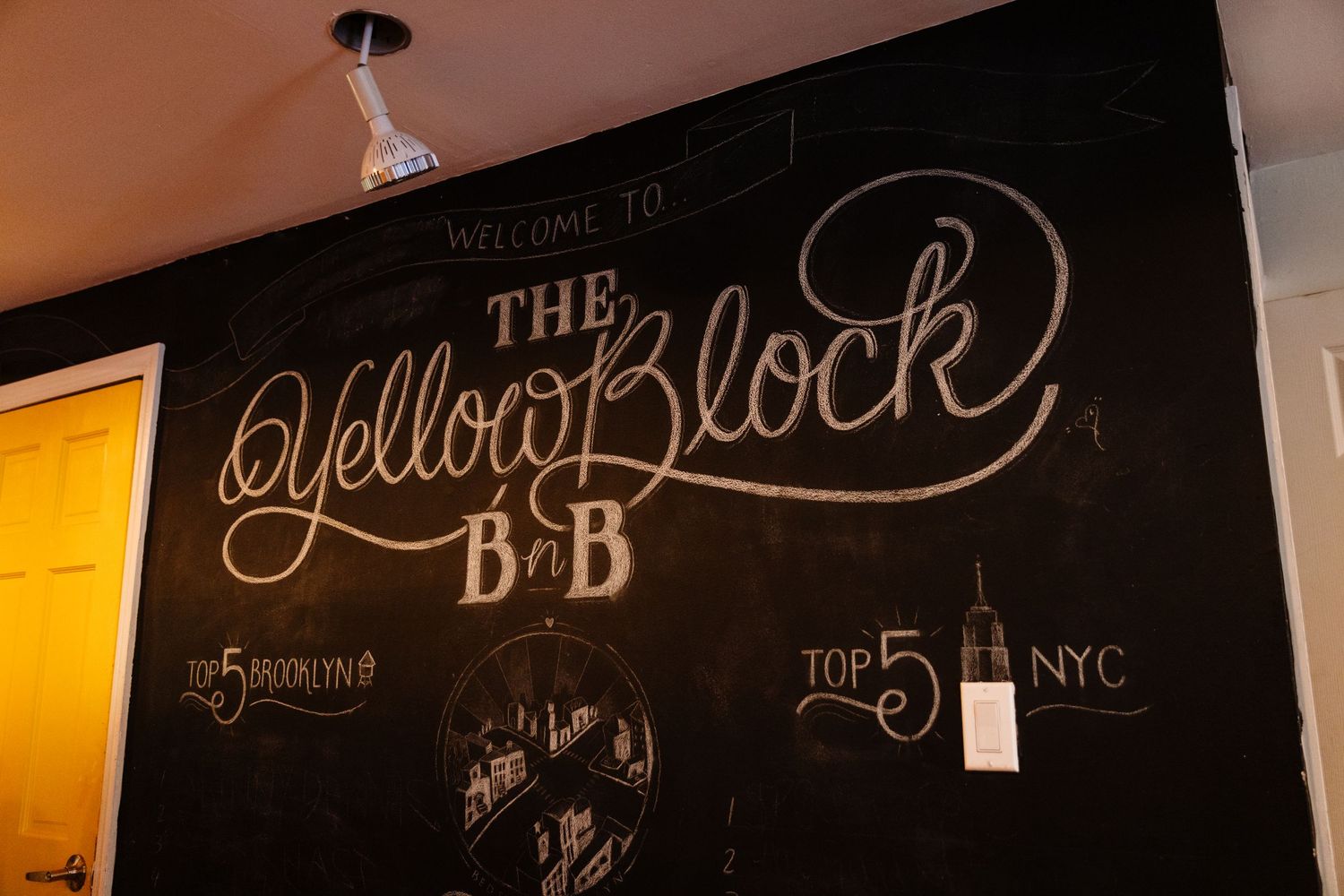 Chalkboard wall with decorative text and design elements in warm lighting.