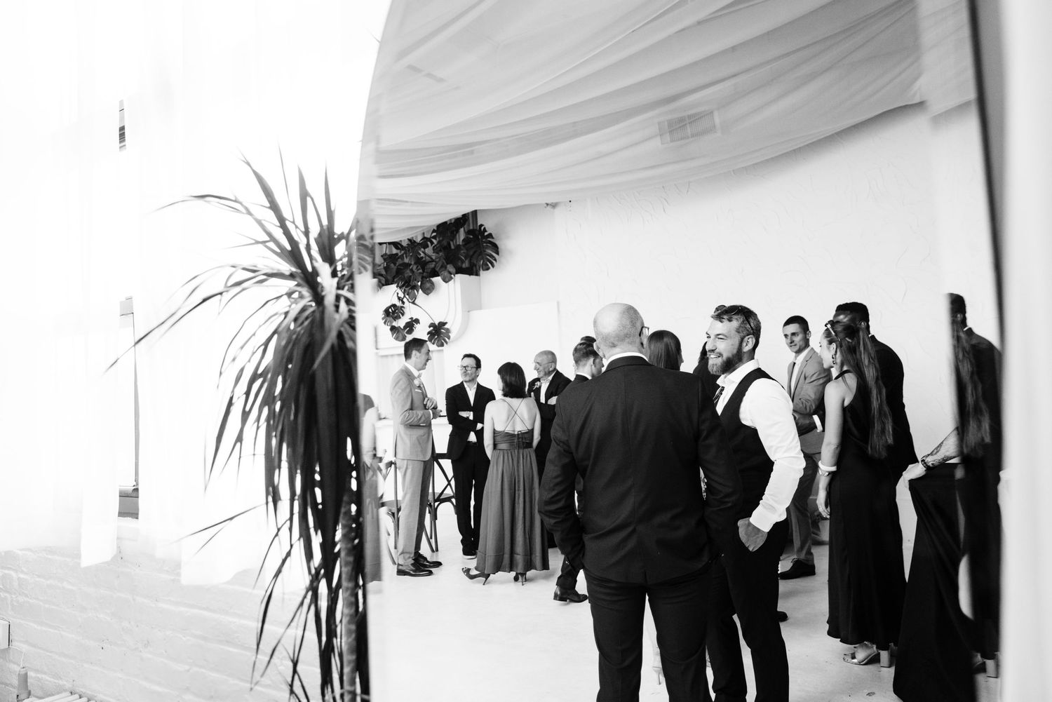 Black and white photo of wedding guests mingling during a reception.