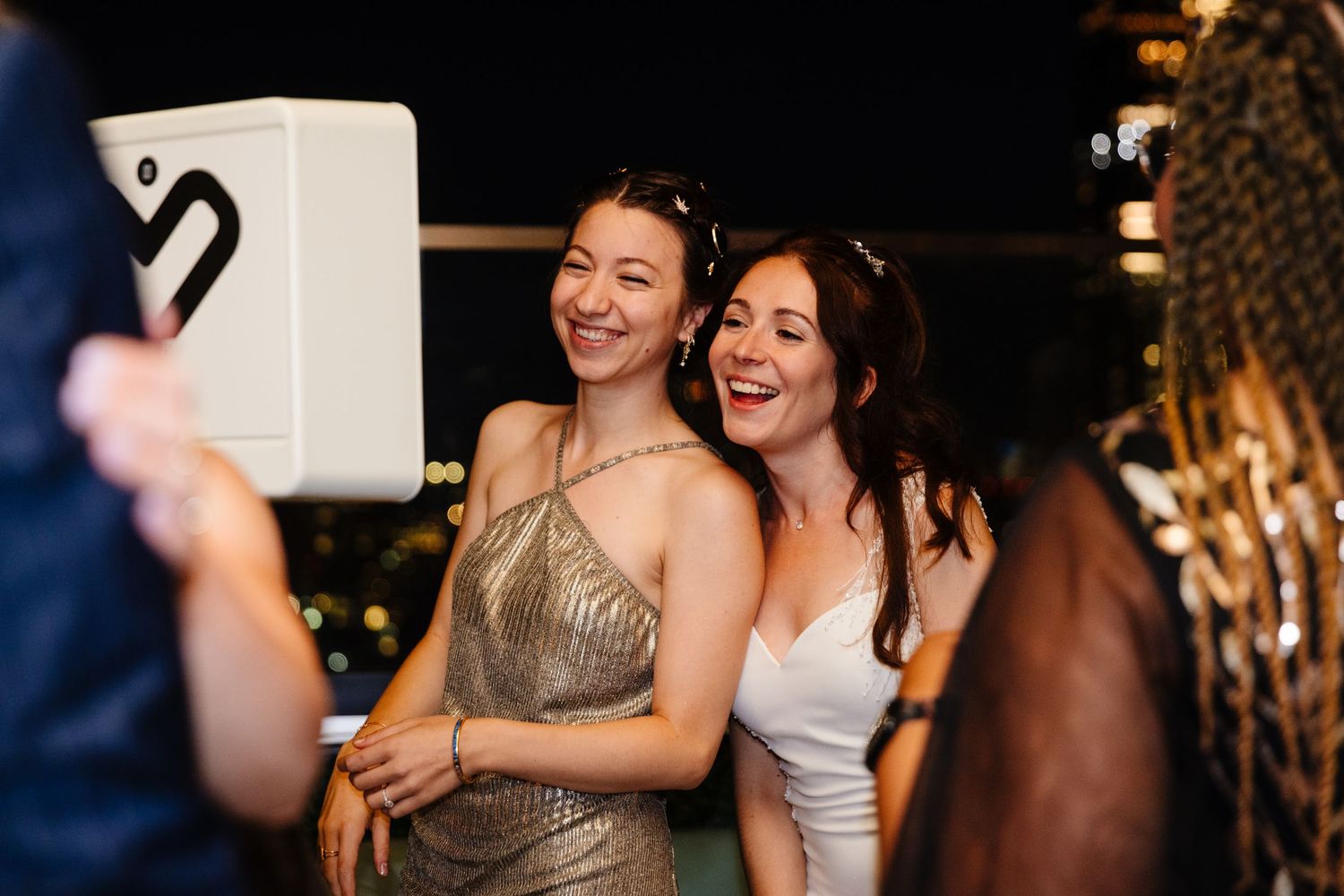 Wedding celebration with guests dancing and embracing on a dimly lit dance floor.
