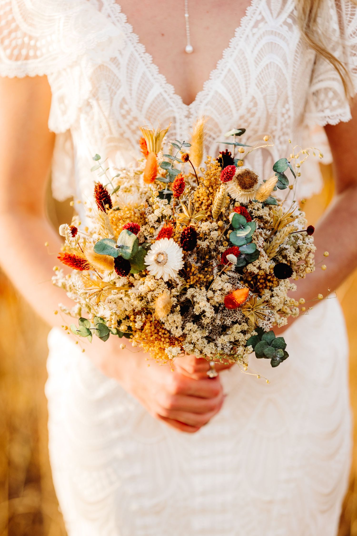 Close-up of a rustic dried flower wedding bouquet with white and burgundy blooms.