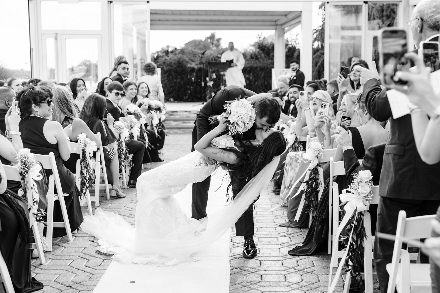 Black and white photo of wedding guests celebrating at an outdoor reception.
