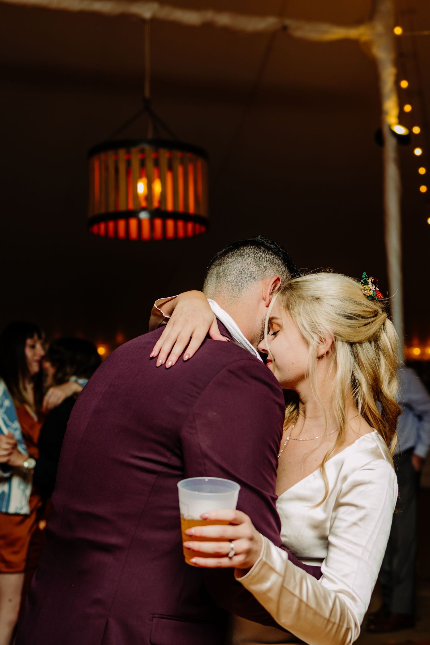 Couple shares an intimate dance moment under warm lighting at their wedding reception.