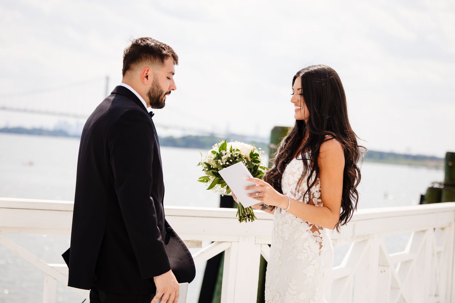 Couple sharing their first look moment on a bright white waterfront deck.