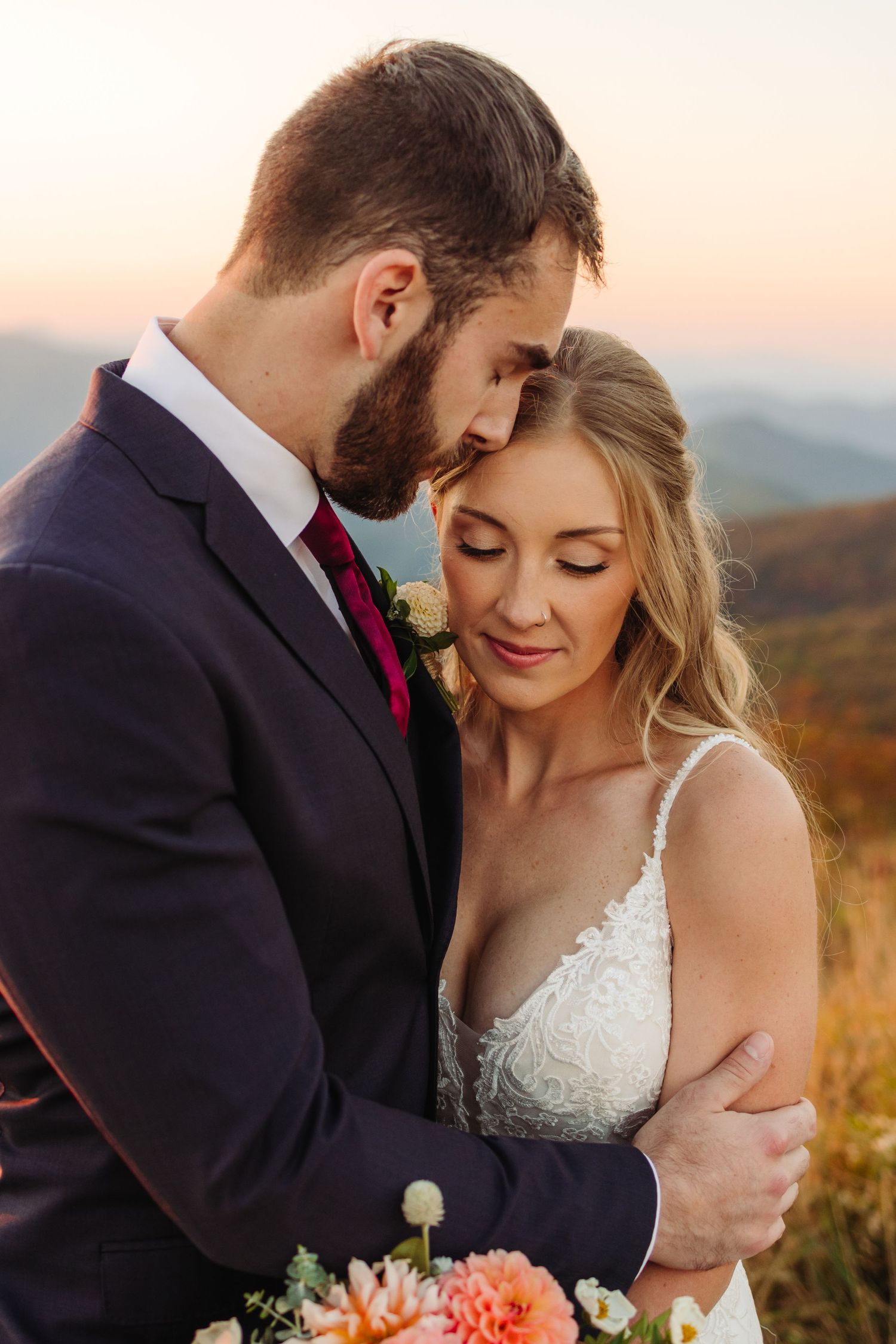 Intimate wedding portrait with soft golden light in mountain meadow setting.