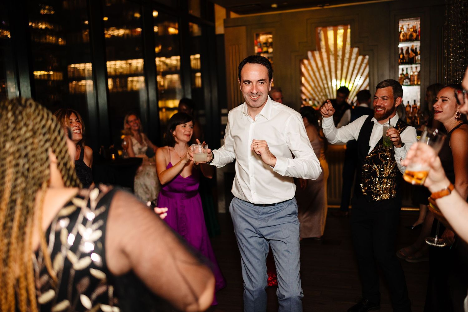 Wedding guests dancing and celebrating in an elegantly decorated venue with art deco details.