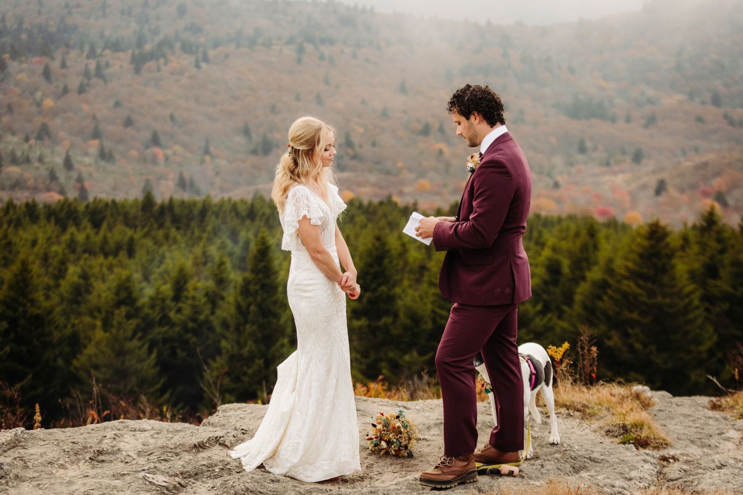 An intimate wedding ceremony unfolds on a rocky mountain overlook with evergreen forest views.