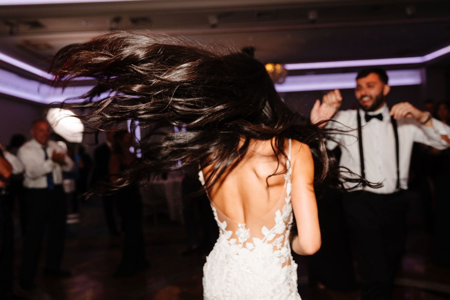 Bride with flowing dark hair dances energetically on the reception dance floor.