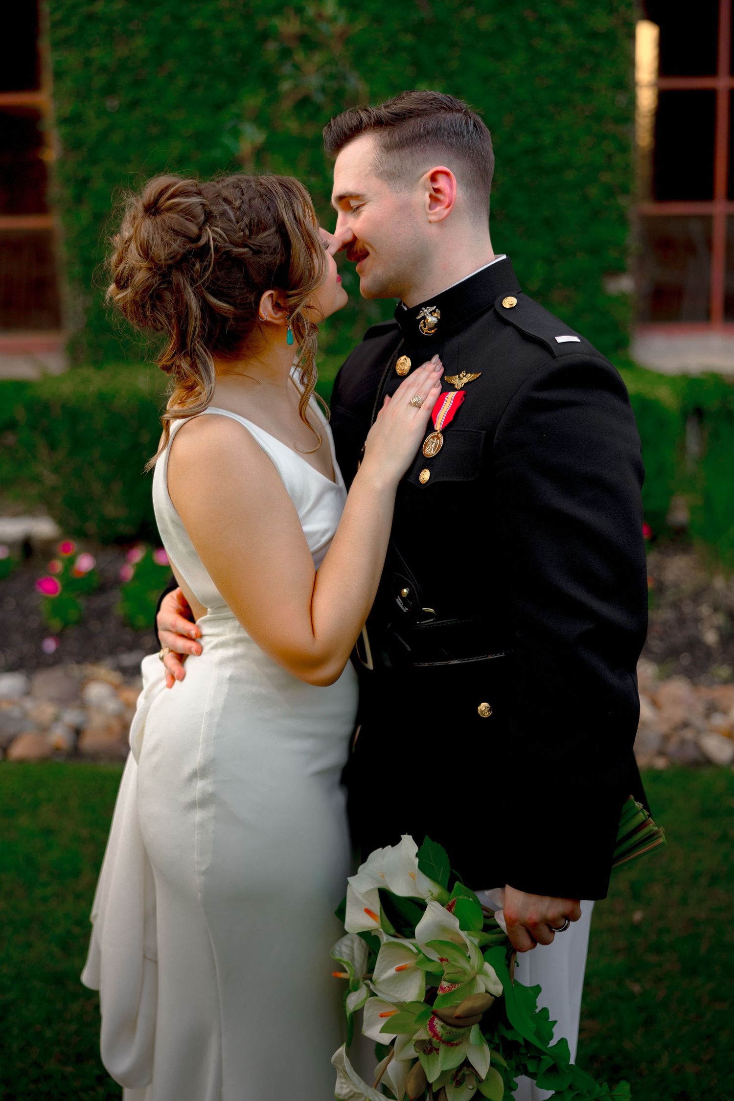 Husband and wife are holding each other at a wedding venue in Montgomery, Texas. They are smiling, he is holding a bouquet of flowers.