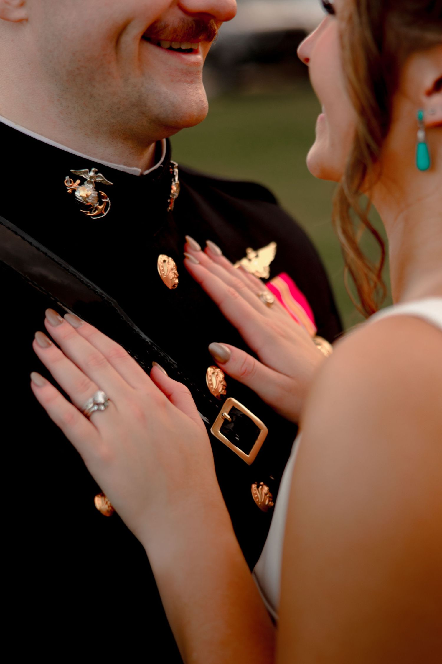 Husband and wife grinning at each other in Montgomery, Texas. He is a marine wearing a uniform, she is resting both her hands on his chest.