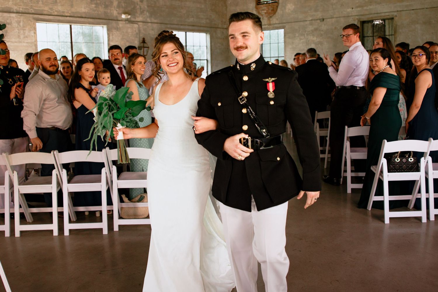 Bride and groom walking down the aisle. They are smiling and walking in the Olde Dobbin Station in Montgomery, Texas.