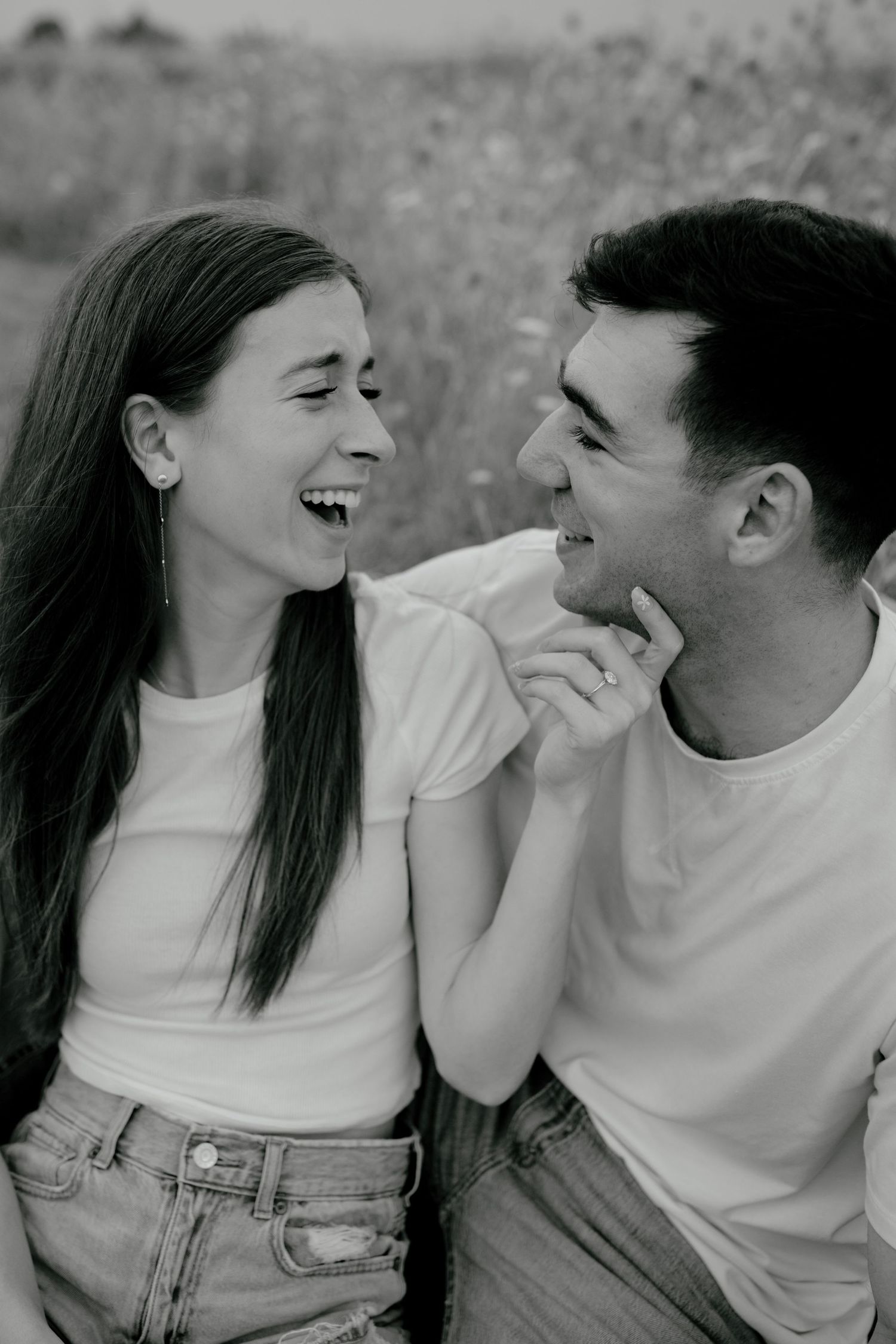Couple sitting in a field in Dallas, Texas, smiling at each other, laughing and enjoying their time together.