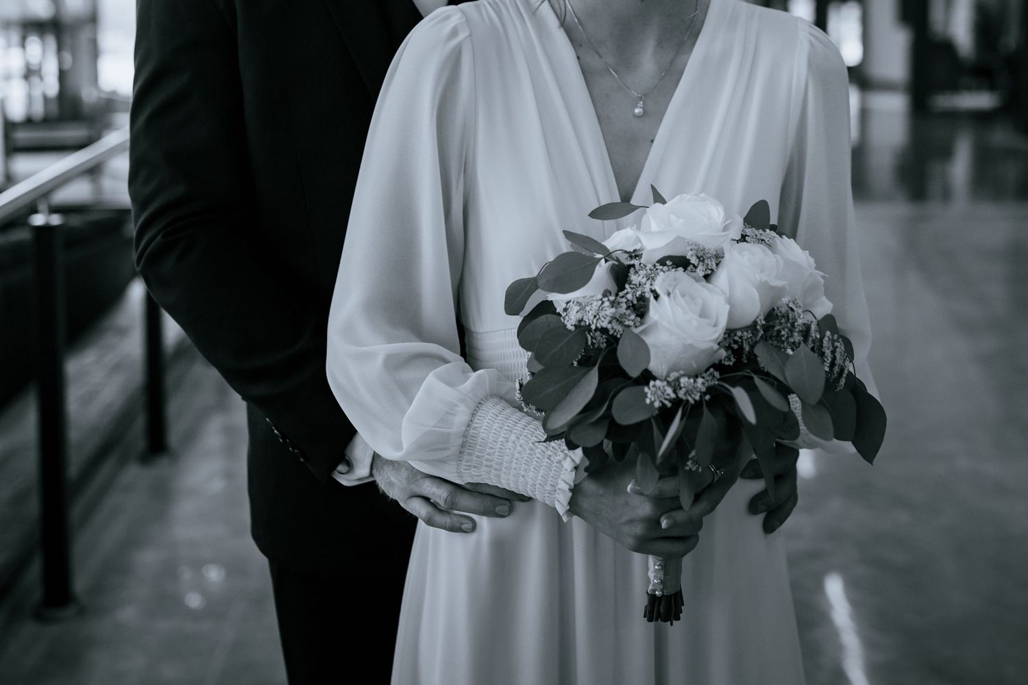 Black and white micro-wedding in a church in College Station, Texas. Groom standing behind the bride while she holds flowers.
