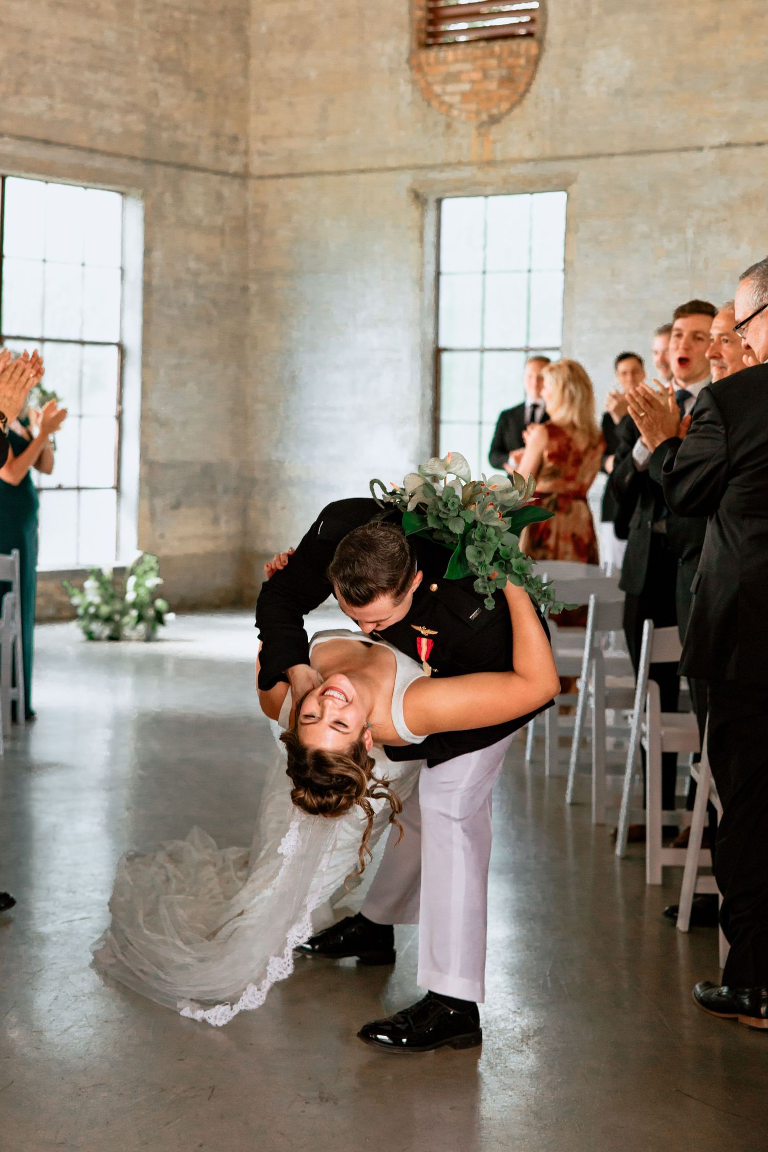 Bride and groom walking down the aisle. The groom dips and kisses the bride in the Olde Dobbin Station in Montgomery, Texas.