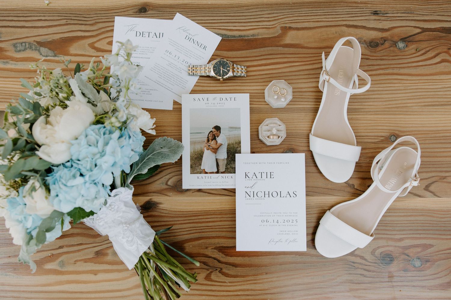 Wedding flat lay with white heels, floral bouquet, invitations, and accessories on rustic wood.
