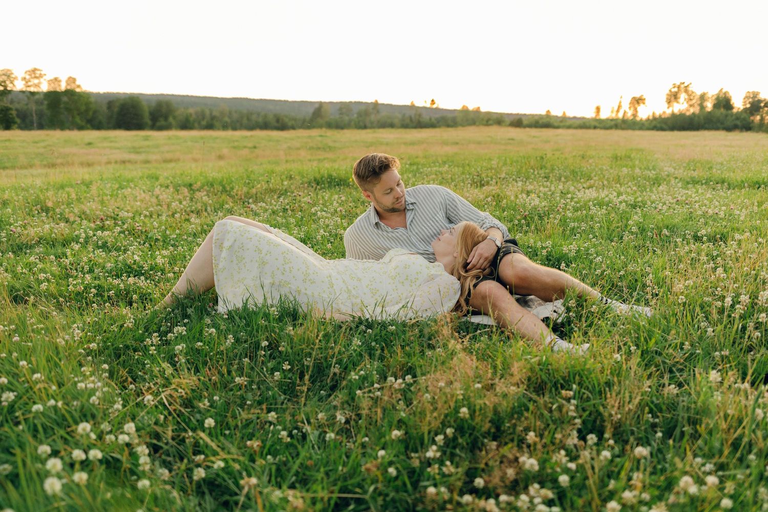 Parfotografering med Martina och Sebastian i Borgvik utanför Karlstad. Hon ligger i hans knä på äng.