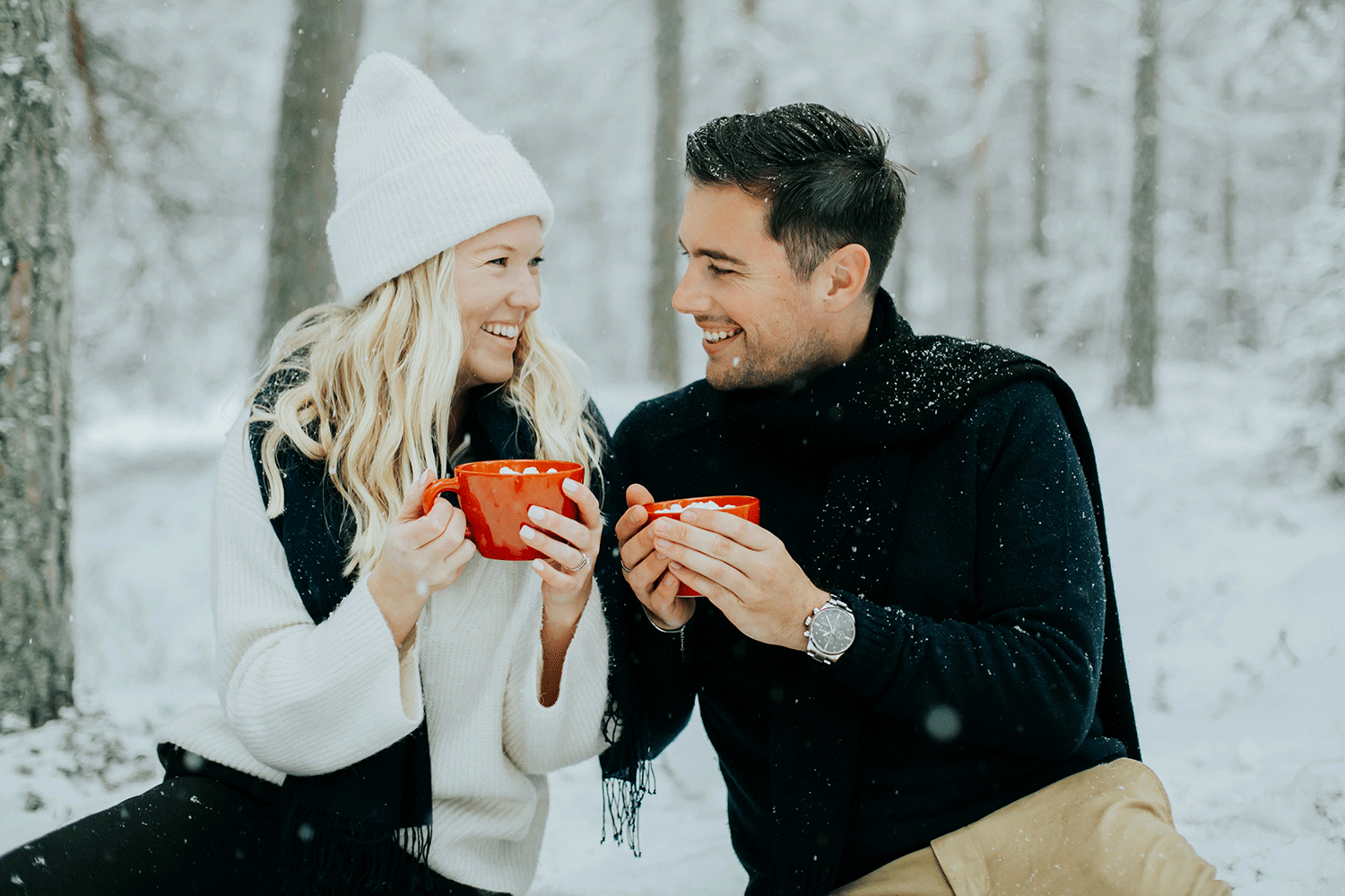 Kärleksfotografering på Skutberget i Karlstad. Man och kvinna som håller i koppar och sitter i snön.