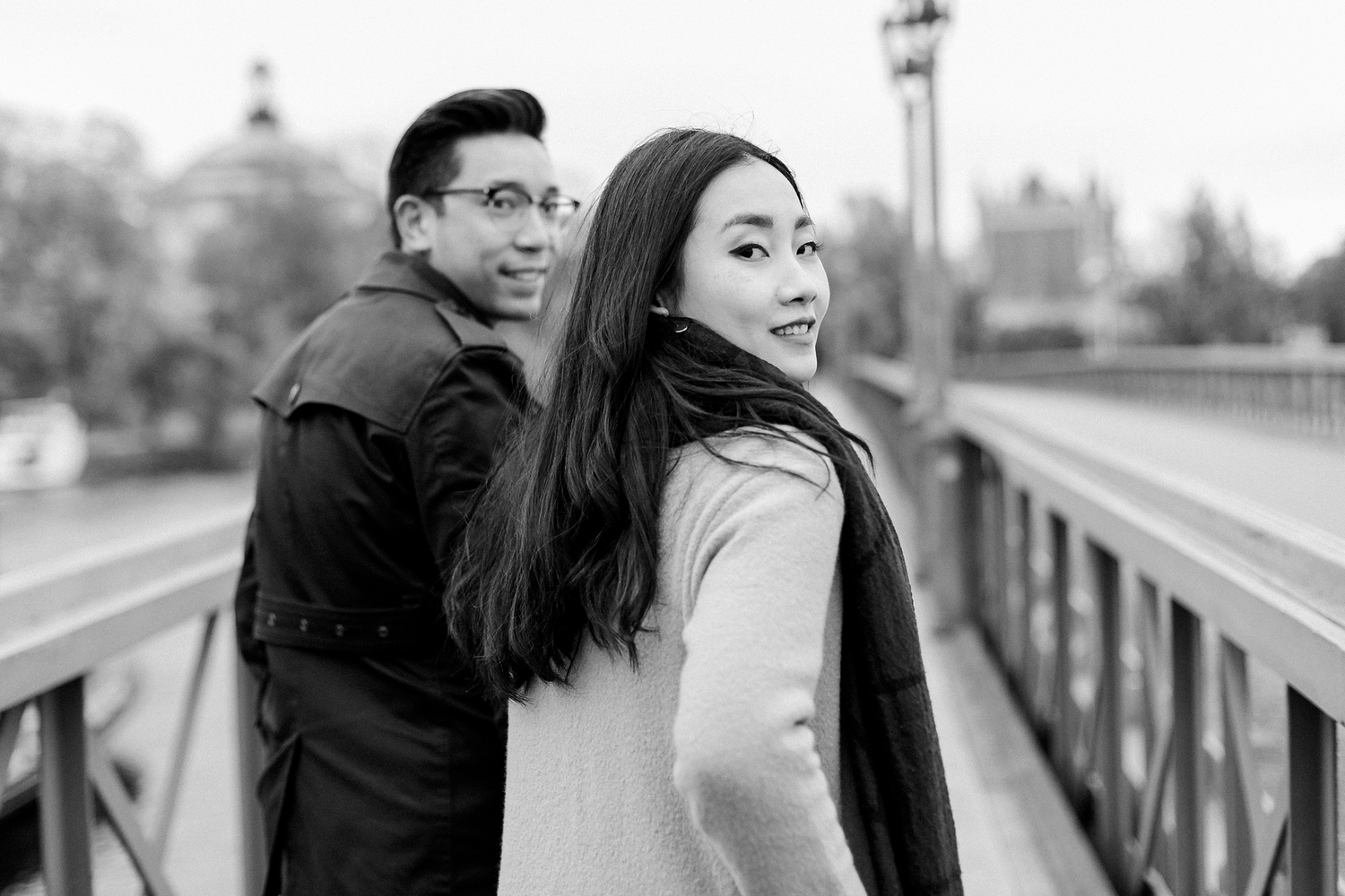 Parfotografering på Skeppsholmesbron. Kvinnan i fokus. Både mannen och kvinnan tittar bakåt mot fotografen. Svartvit.