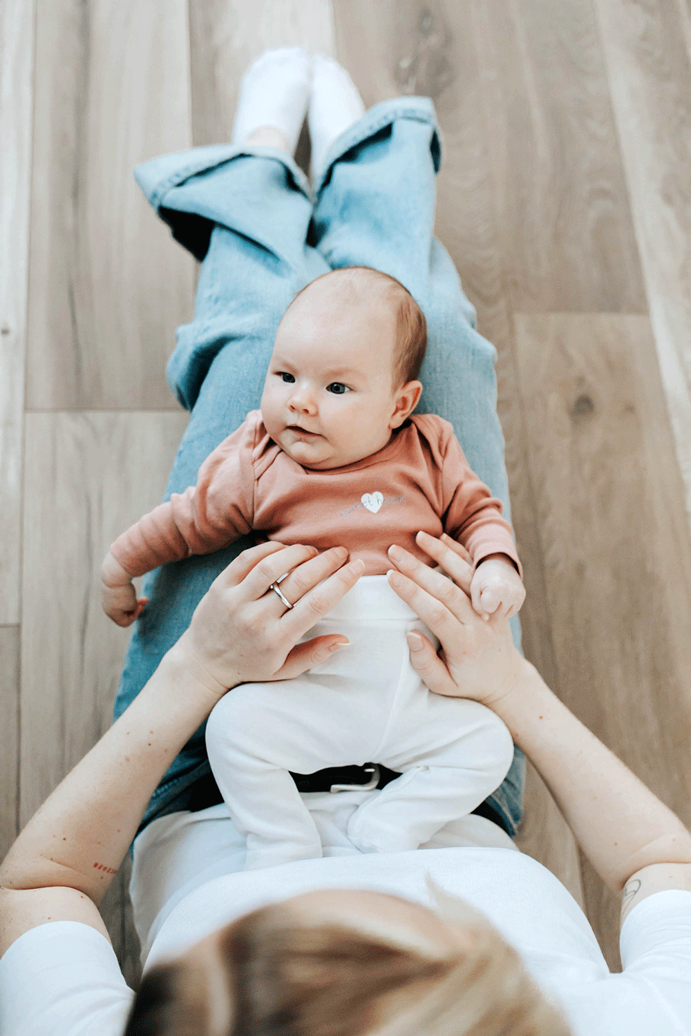 Bebis som ligger i mammas knä. Fotograferat uppifrån.