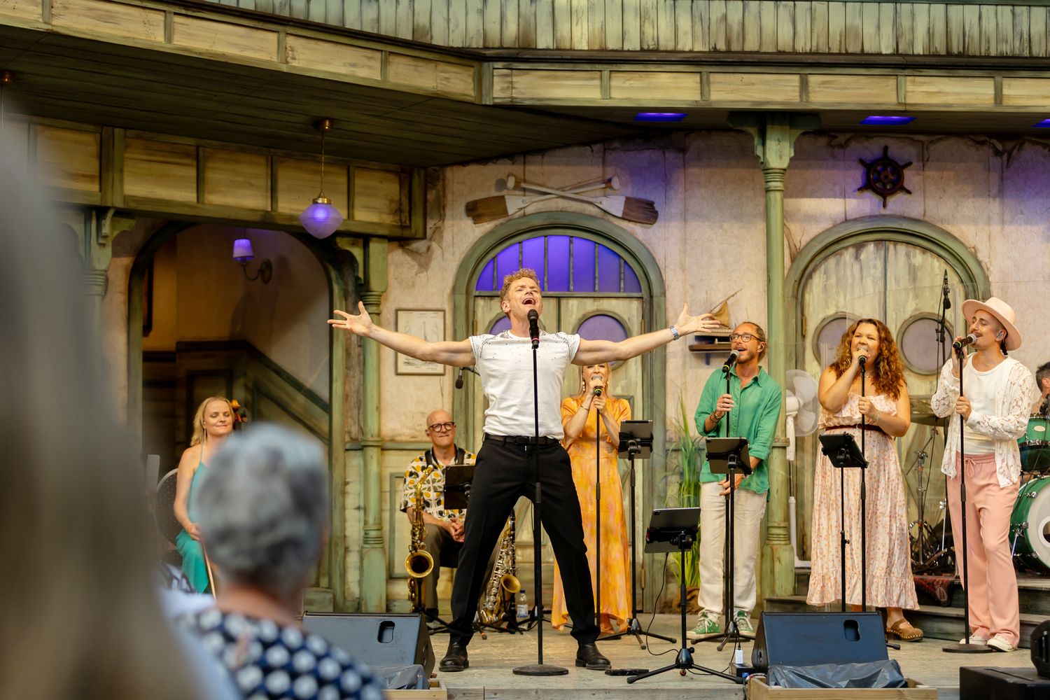 Musikalkväll med Peter Johansson o Emmi Christensson. Peter sjunger i micken som är i stativet och håller armarna rakt ut.