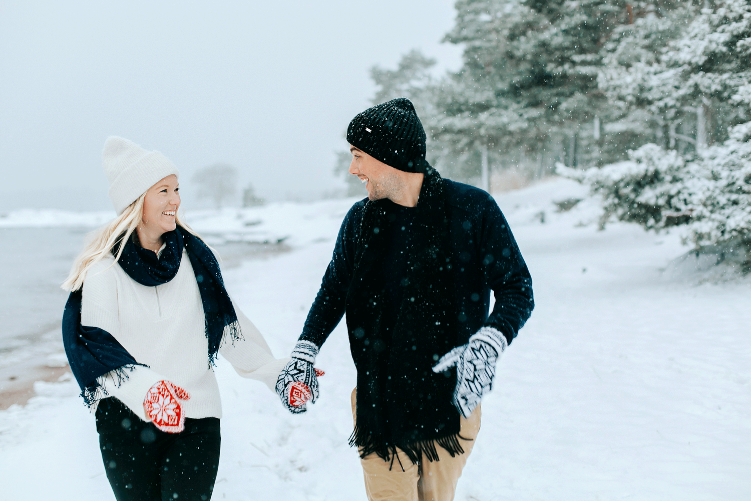 Kärlekspar på vintrigt Skutberget. Går bredvid varandra hand i hand och skrattar.