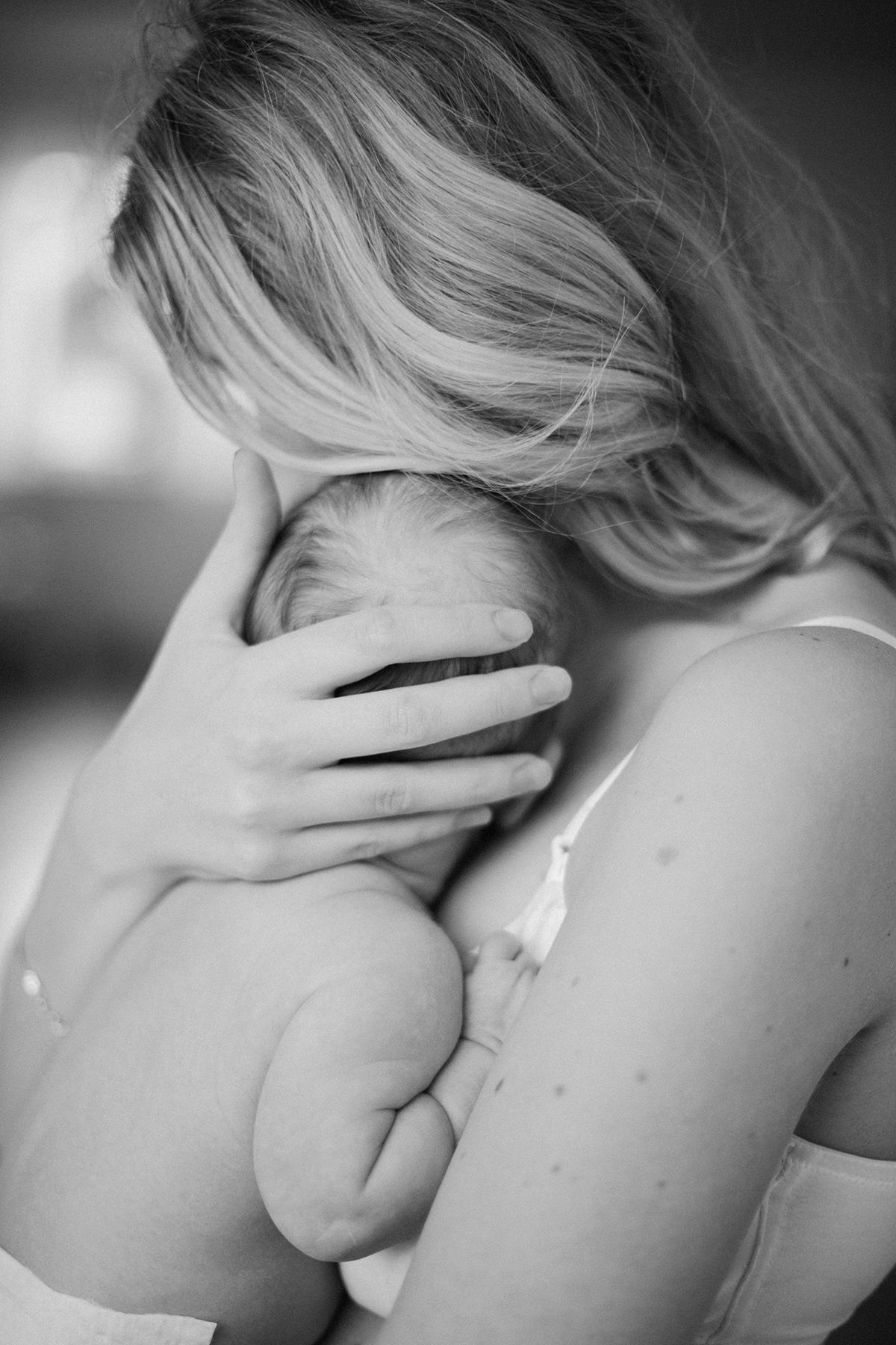 Mamma som håller om sin nyfödda bebis. Svartvit. Båda syns bakifrån.