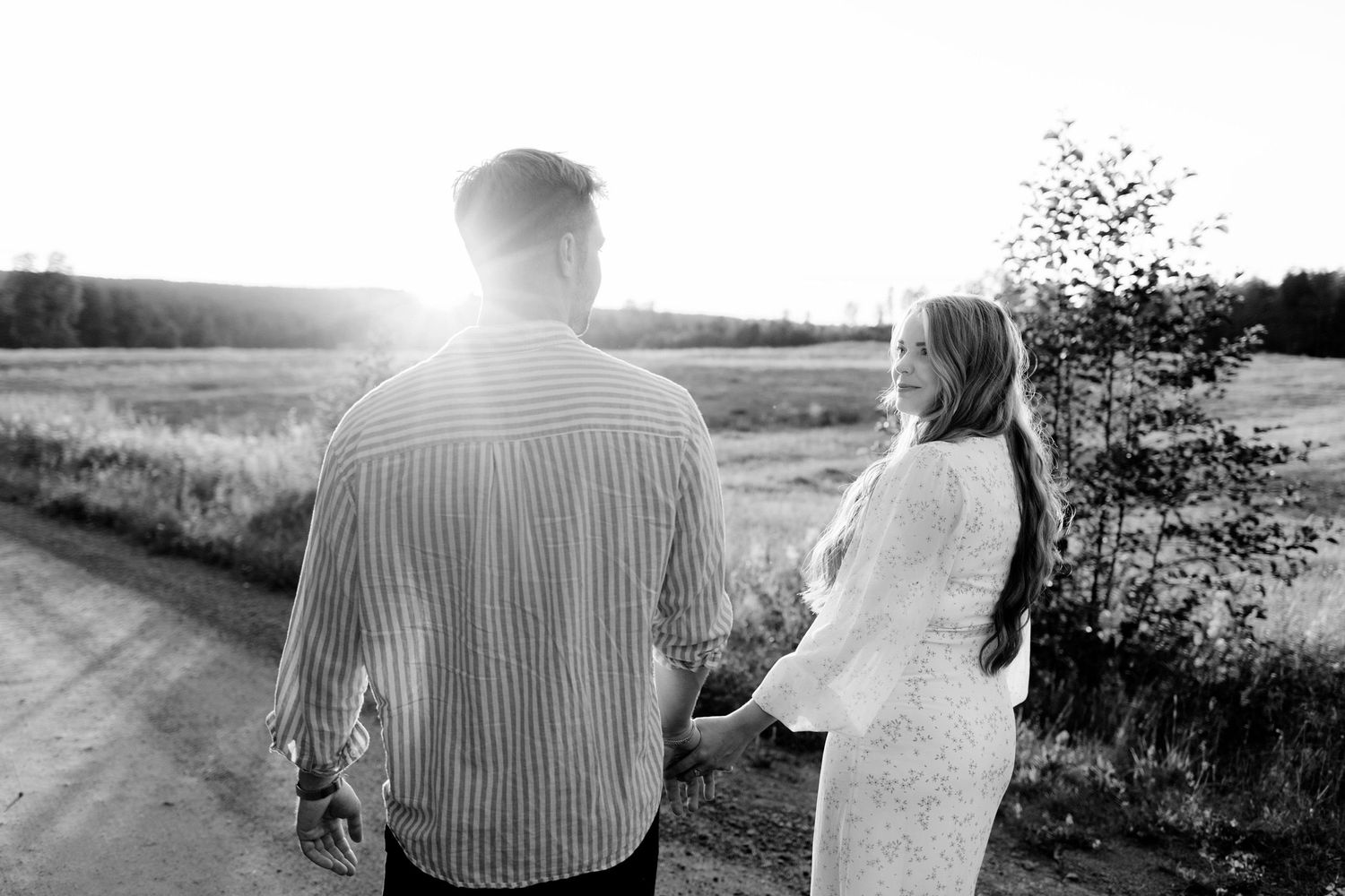 Parfotografering med Martina och Sebastian i Borgvik utanför Karlstad. Gående på grusväg i solnedgång. Hon tittar på honom.