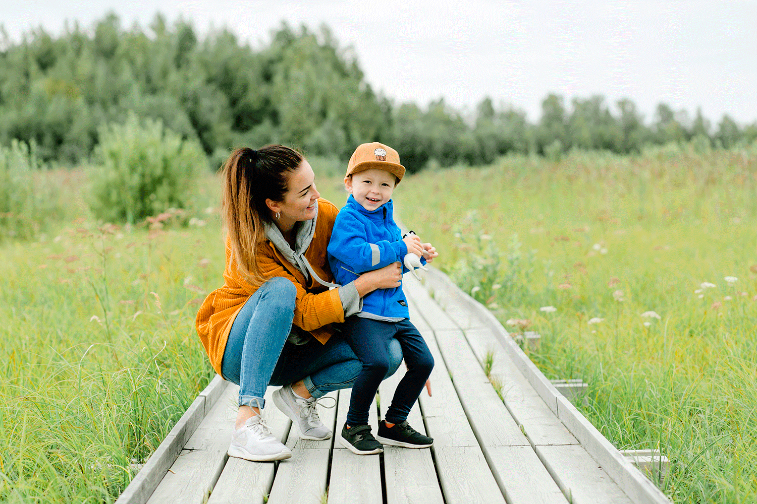Mamma och son på spång i Mariebergsskogen. Båda har starka färger på sig. Han sitter på hennes knä.