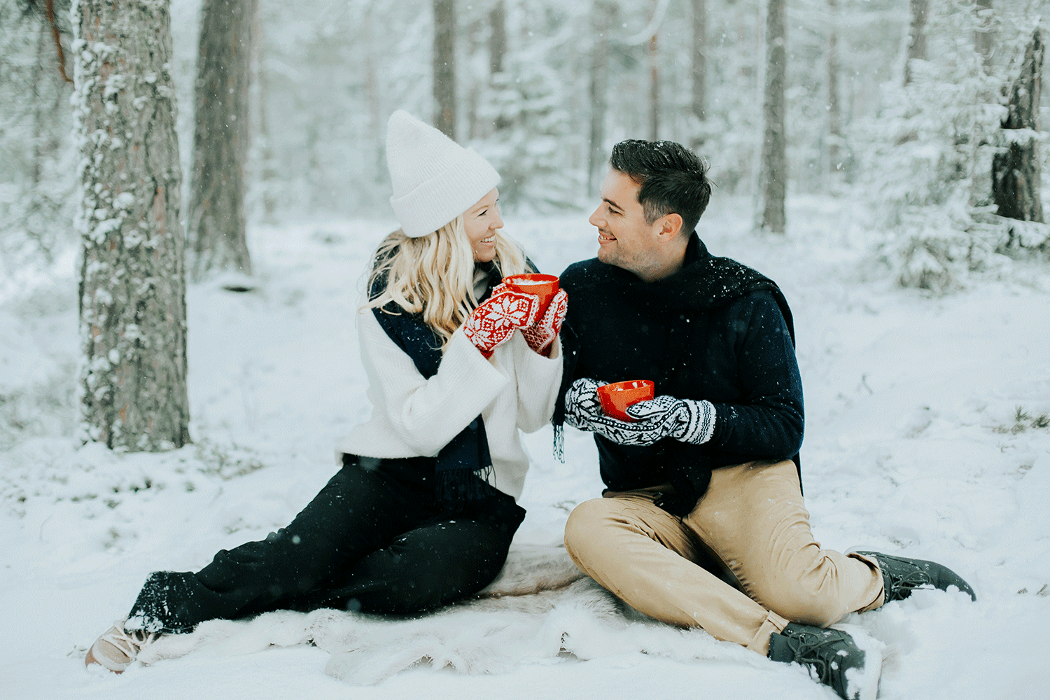 Kärleksfotografering på Skutberget i Karlstad. Man och kvinna som håller i koppar och sitter i snön.