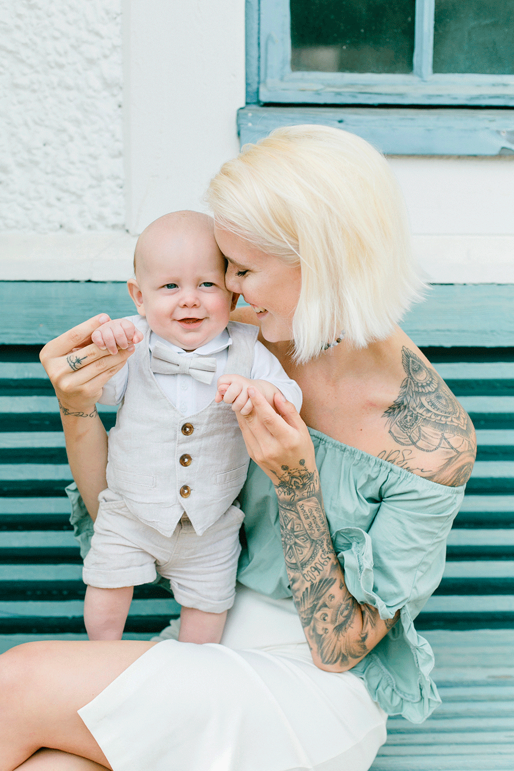 Mamma med sin bebis. Båda är uppklädda. Bebisen har fluga och väst. Hon lutar sig in mot honom.
