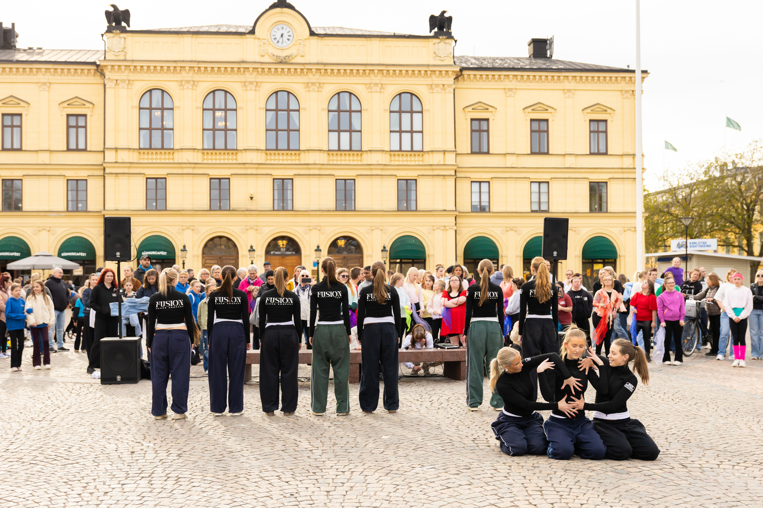 Dansens dag på stora torget i Karlstad. Dangruppen Fusion. Tre av dansarna sitter på backen, resten står.