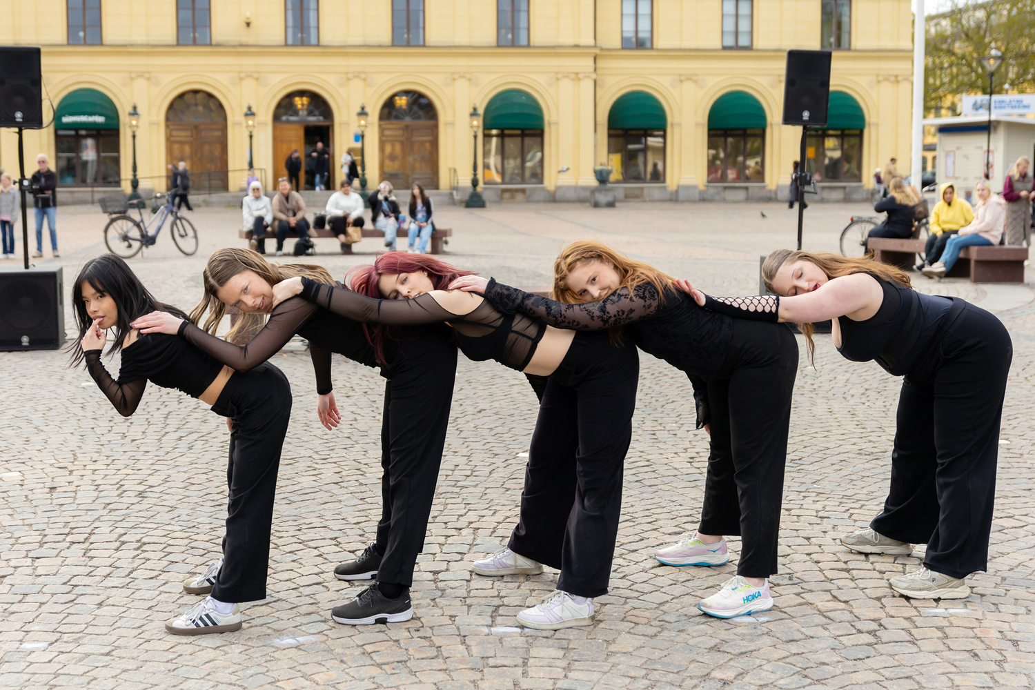 Dansens dag på stora torget. Dansare från Karlstads Universitet. Dansåret och Danspedagogiska. Kläddai helsvart. Lutar sig mot varandra.