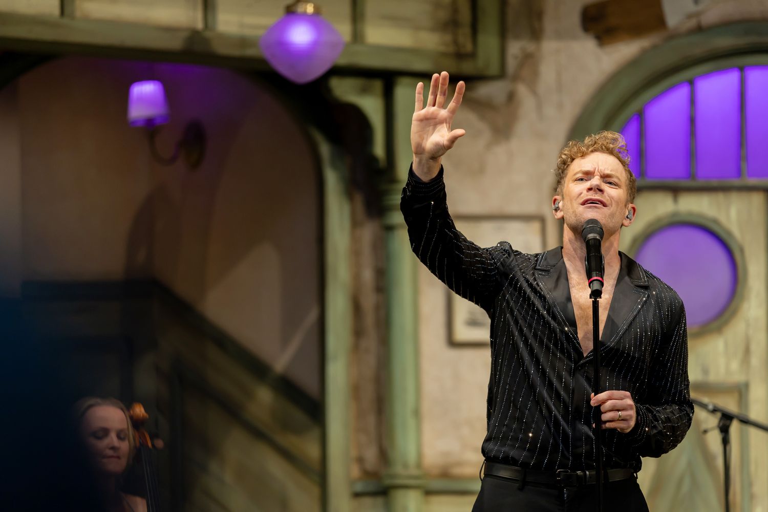 Musikalkväll med Peter Johansson o Emmi Christensson. Peter sjunger med en hand sträckt mot himlen.