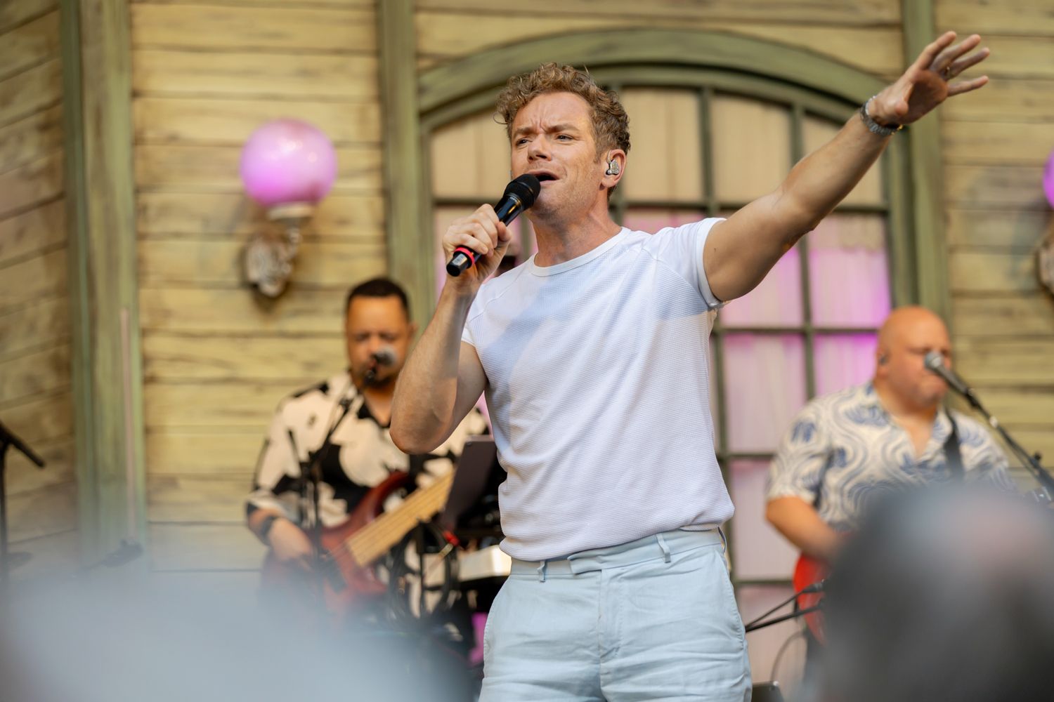 Musikalkväll med Peter Johansson o Emmi Christensson. Peter sjunger med en armen rakt ut. Vit t-shirt och blåa byxor.