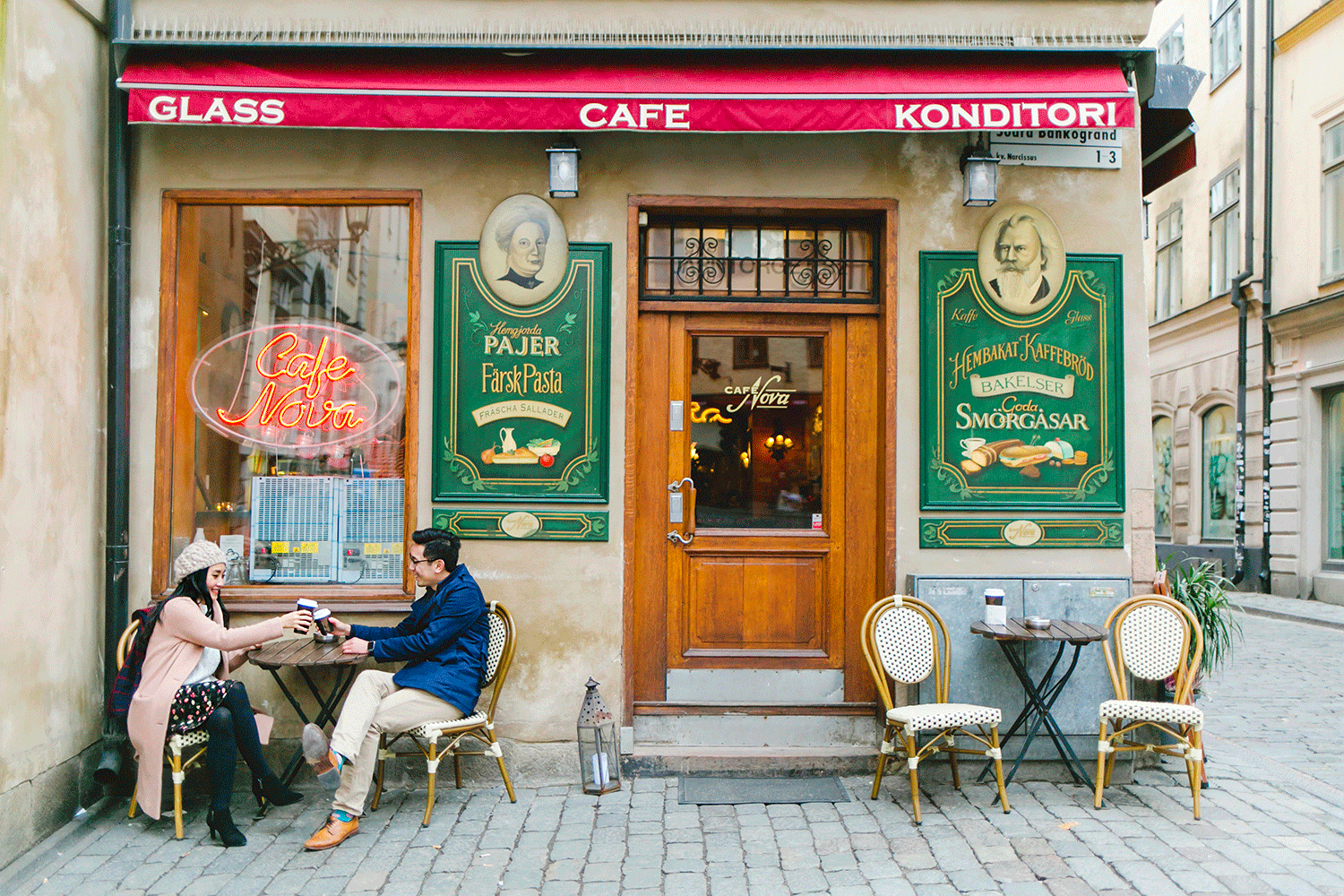 Verksamhetsbild Cafe Nova i gamla stan. Par som sitter framför caféet och skålar med varandra.