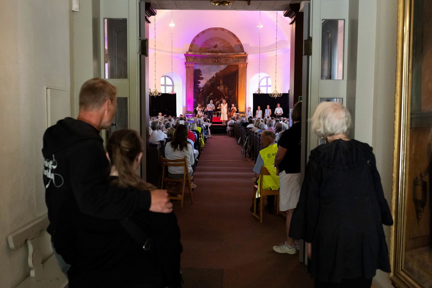 Sommarkonsert med Peter Johansson och Matilda Grün 2025. Kusiner och familj. Fotograf Rebecca Nordin. Familjen tittar på.