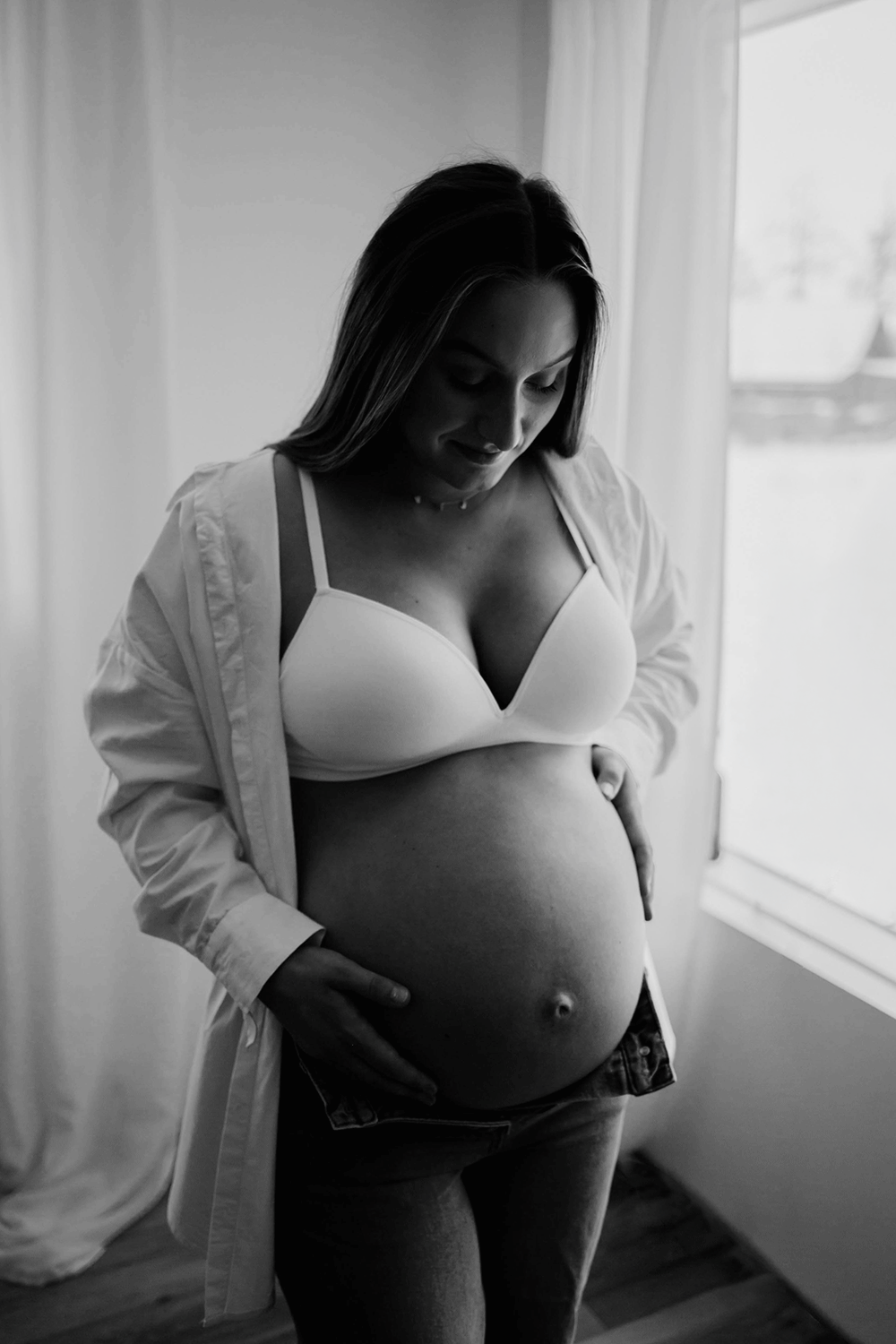 Gravid kvinna som håller under sin mage. Svartvit bild.